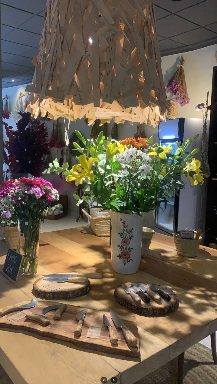 Cuchillos artesanales sobre troncos de madera, junto a las flores
