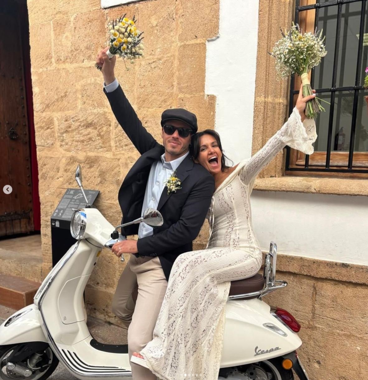 Novios en una Vespa levantando sus ramos